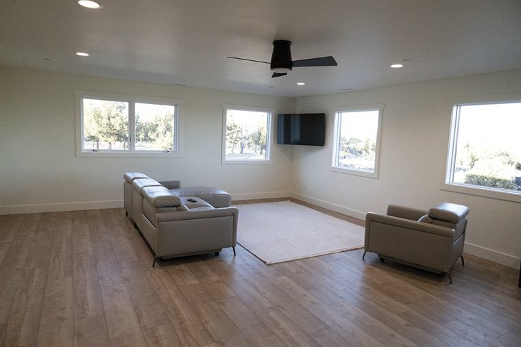 Open bonus room with wood-look floors, a ceiling fan and a mounted TV