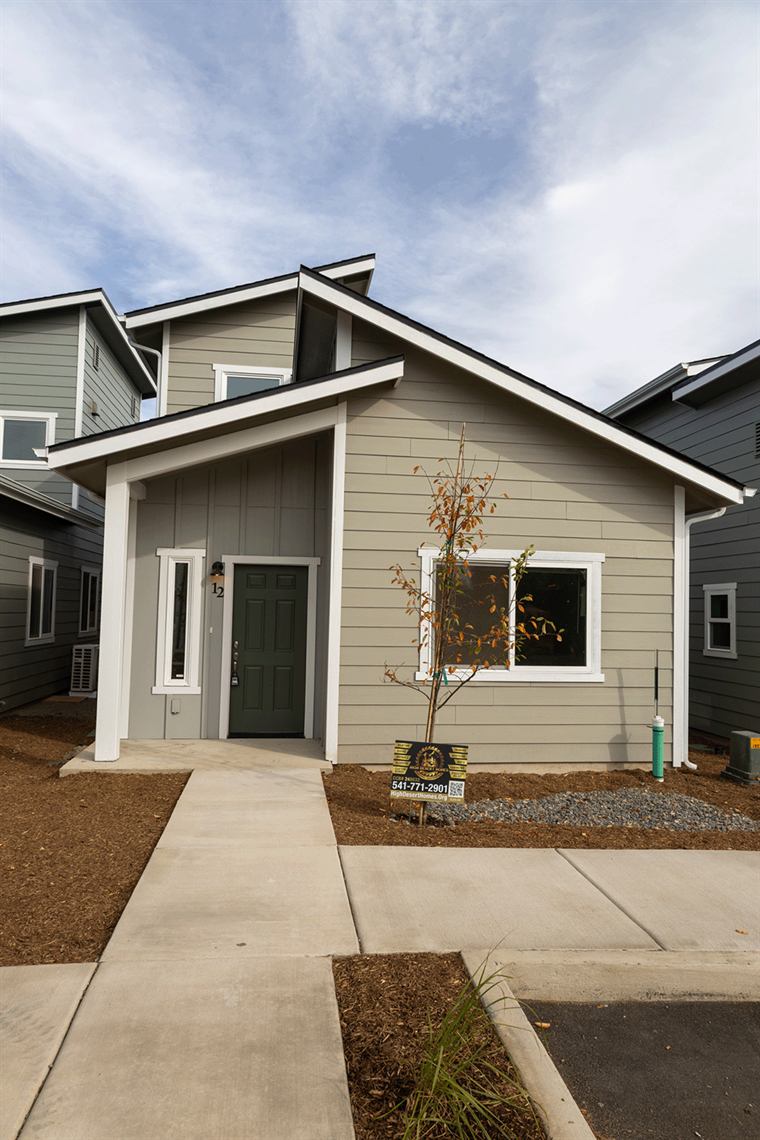 Gray Habitat home with a front porch and walkway