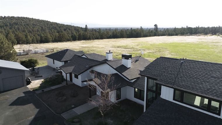 Aerial view of the remodeled ranch home's neighborhood with open fields beyond