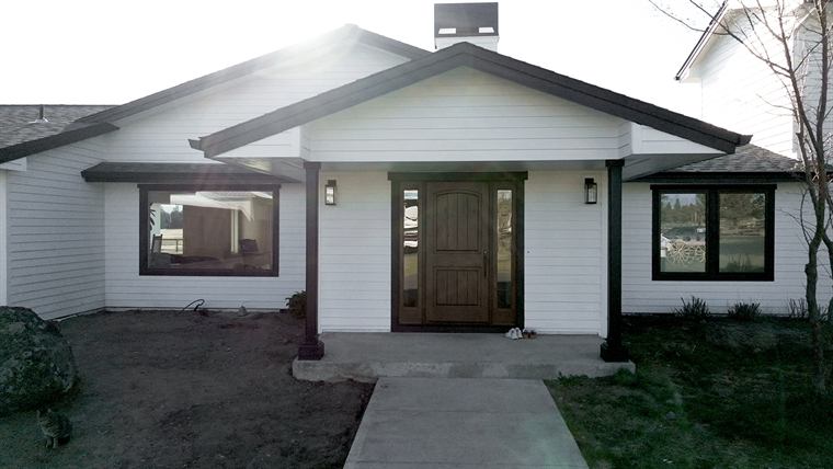 Front of the remodeled white ranch house with a new wood door