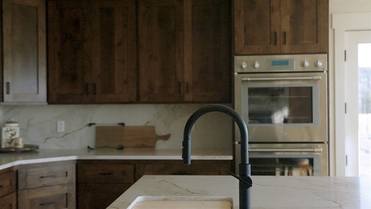 Kitchen with dark wood cabinets, a wall oven and a black faucet
