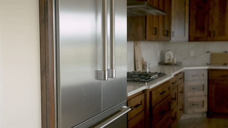 Stainless refrigerator beside dark wood cabinets and a gas cooktop
