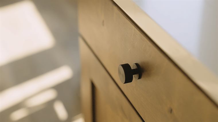 Close-up of a black cabinet knob on light wood