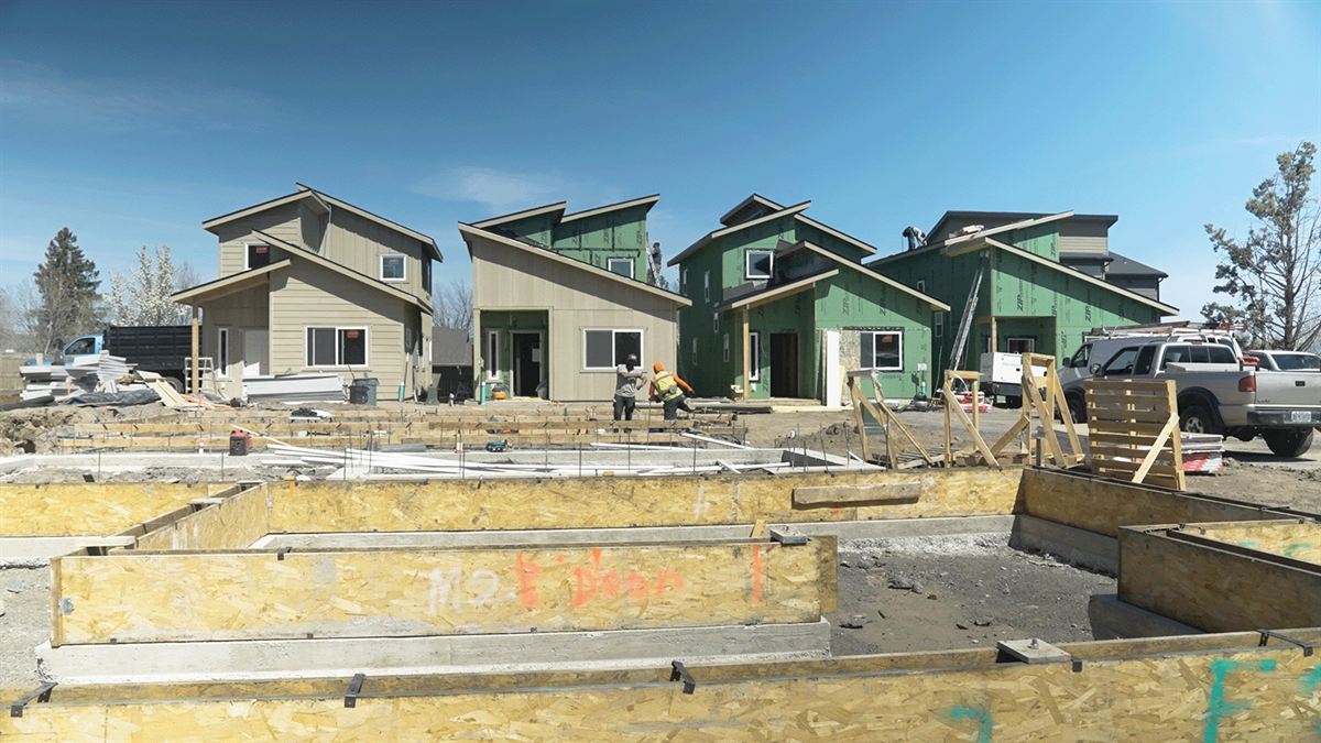 New homes going up on a construction site under a clear sky