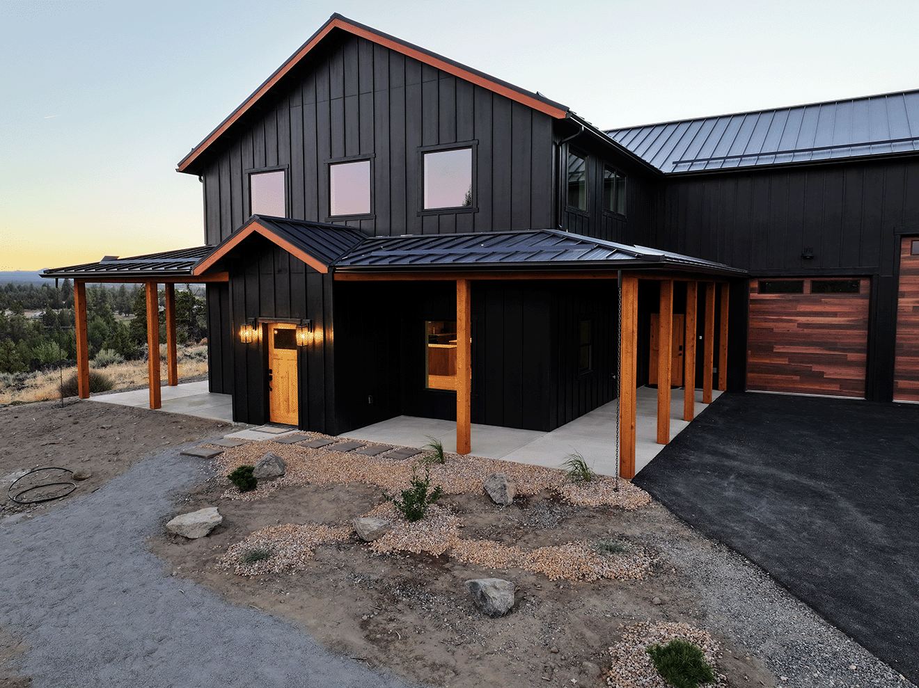 Barndominium with dark siding and warm lights at dusk