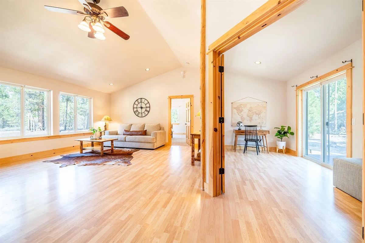 Bright living room with light wood floors, a wood-trimmed doorway and large windows