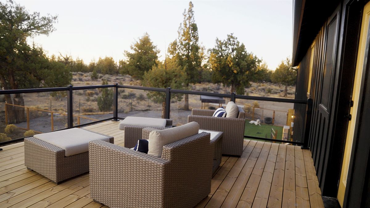 Covered back deck with outdoor furniture overlooking juniper trees
